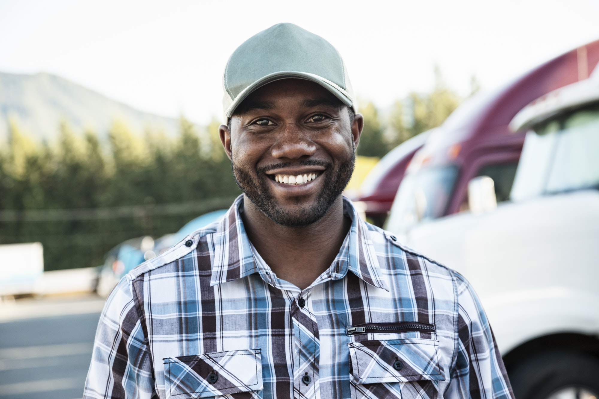 Black man truck driver near his truck parked in a parking lot at a truck stop