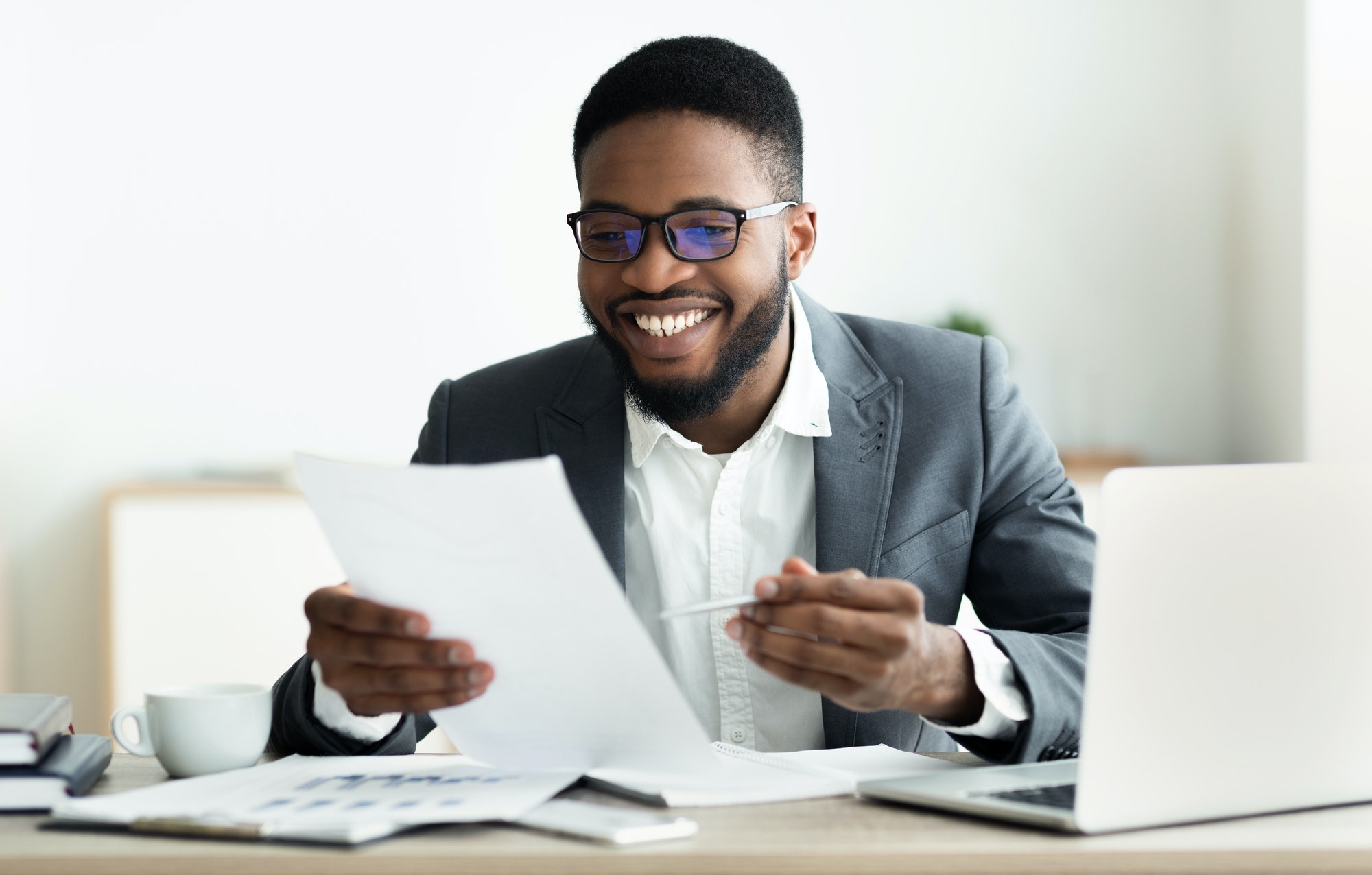 Smiling black businessman checking reports in modern office